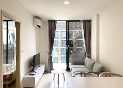 Modern living room with a gray sofa, TV, air conditioning, and large windows