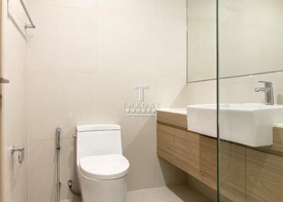 Modern bathroom with a toilet, sink, and wooden cabinetry