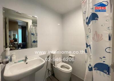 Modern bathroom with white fixtures and a nautical-themed shower curtain