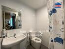 Modern bathroom with white fixtures and a nautical-themed shower curtain