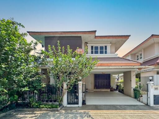 Two-story house with a carport and surrounding greenery