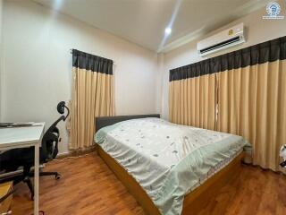 A well-furnished bedroom with a double bed, desk, and office chair.