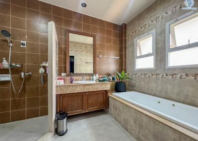 Spacious bathroom with bathtub, large mirror, and extensive tiling