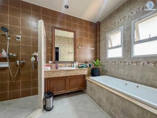 Spacious bathroom with bathtub, large mirror, and extensive tiling