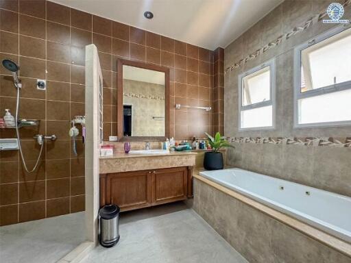 Spacious bathroom with bathtub, large mirror, and extensive tiling