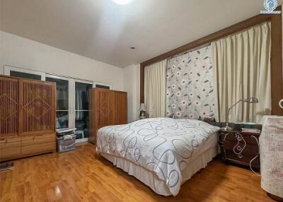 A spacious bedroom with hardwood flooring, a large bed, and ample storage