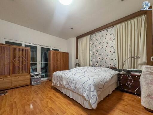 A spacious bedroom with hardwood flooring, a large bed, and ample storage