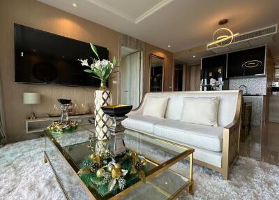 Elegant and modern living room with glass coffee table, decorative items, and mounted TV