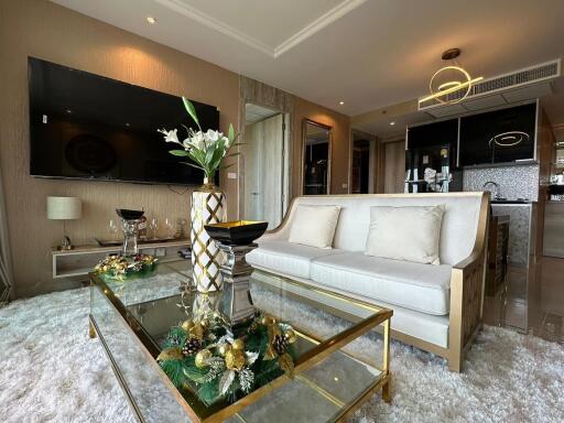 Elegant and modern living room with glass coffee table, decorative items, and mounted TV