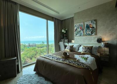 Bedroom with large window and view of greenery and ocean