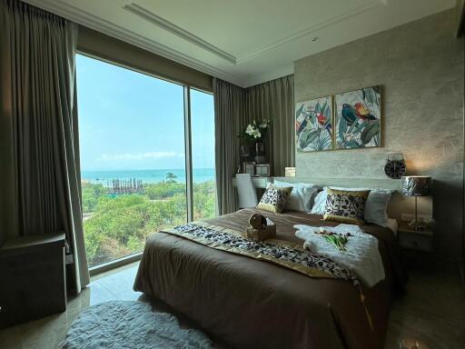 Bedroom with large window and view of greenery and ocean