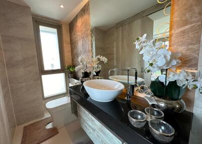 Modern bathroom with marble tiles, bowl sink, and decorative orchids