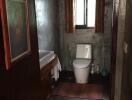 A bathroom with a toilet, sink, and window.