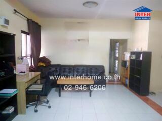 Living room with black sofa, wooden coffee table, desk, chair, and bookshelves