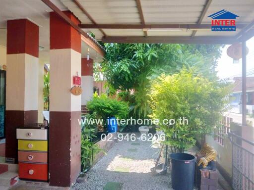 Outdoor pathway with colorful drawers, green plants, and a real estate sign