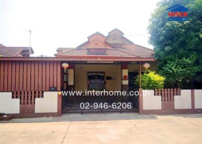 Front view of a residential house with a gated entrance and visible contact information