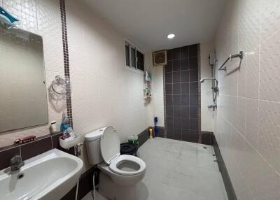 Modern bathroom with white tiles, a sink, toilet, and shower area