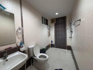 Modern bathroom with white tiles, a sink, toilet, and shower area