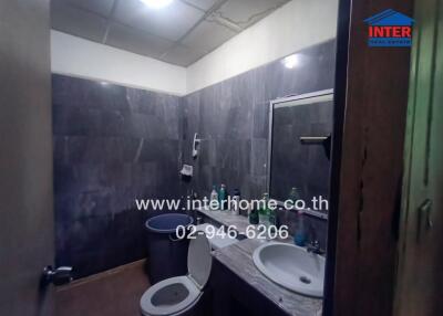 Bathroom with dark tiled walls and basic fixtures