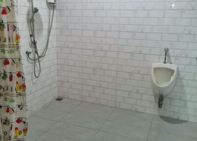 Spacious bathroom with tiled walls and floor, shower, and urinal