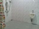 Spacious bathroom with tiled walls and floor, shower, and urinal