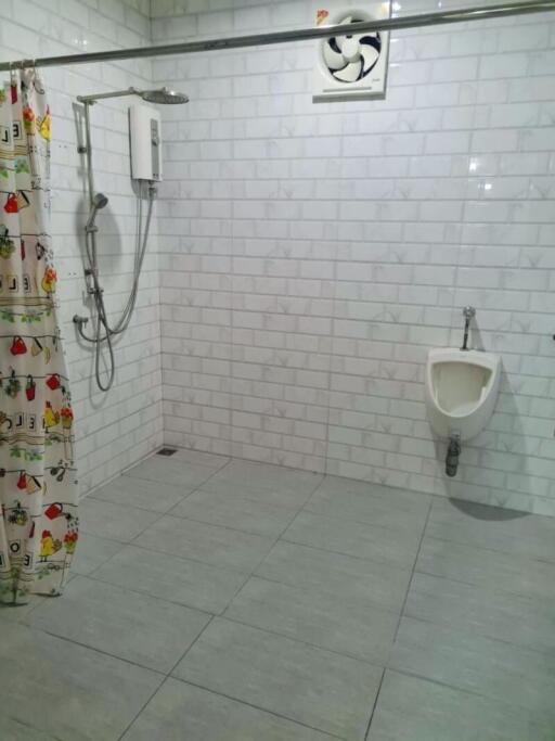 Spacious bathroom with tiled walls and floor, shower, and urinal