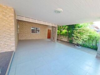Spacious covered outdoor area with tiled floor and garden view