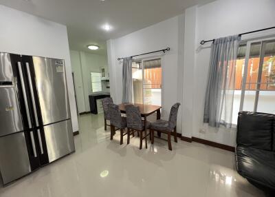 Modern kitchen and dining area with stainless steel refrigerator, dining table and chairs, and large windows