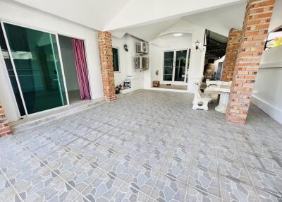 Spacious outdoor patio area with tiled flooring and partial brick walls