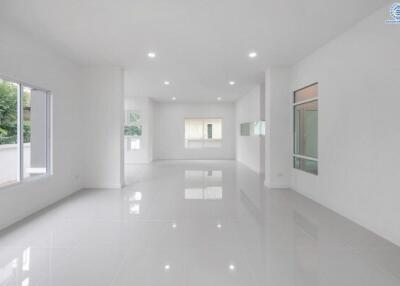 Spacious and empty modern living area with large windows and white tile flooring