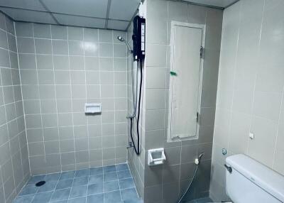 Bathroom with tiled walls and floor, featuring a shower area and a toilet