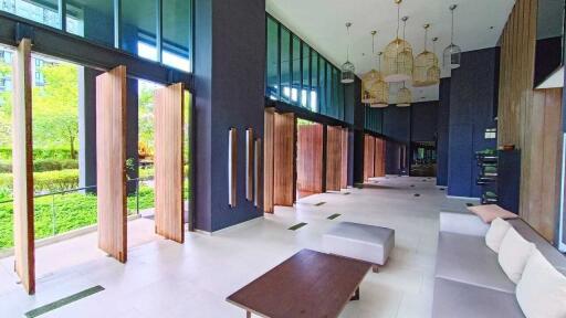 Modern communal living space with large windows, sliding wooden doors, and comfortable seating.