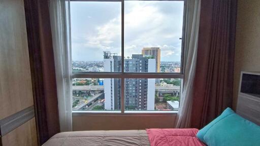 Bedroom with a view of city buildings through a large window