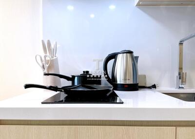 Modern kitchen with countertop stove, electric kettle, and hanging utensils