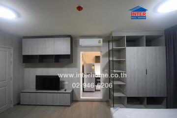 Modern living area with built-in storage and TV setup, view of kitchen entrance