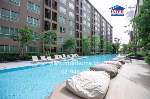 Outdoor pool area with loungers and beanbag chairs in front of apartment building