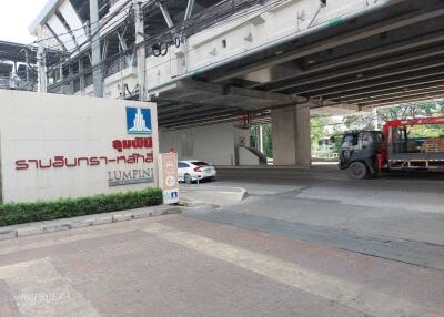 Entrance to Lumpini building with adjacent road and parked vehicles