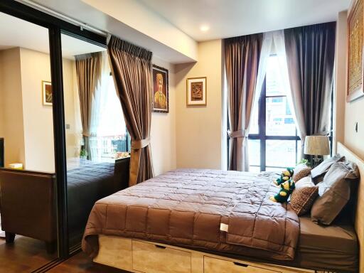 Cozy bedroom with a large bed, mirrored closet, and sizeable windows with curtains
