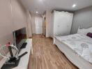 Spacious bedroom with wooden flooring, wardrobe, and TV