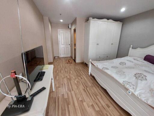 Spacious bedroom with wooden flooring, wardrobe, and TV