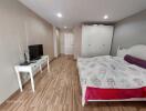 Modern bedroom with wooden flooring, TV, and white wardrobe