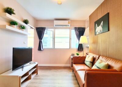 Modern living room with brown leather sofa, flat-screen TV, and wall shelves