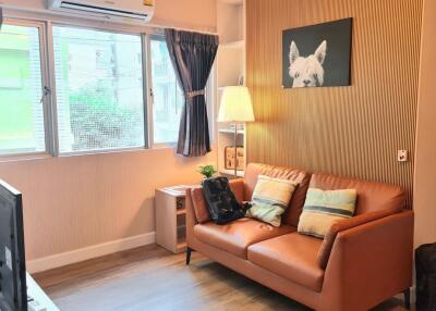 Cozy living room with a brown sofa, pillows, lamp, and wall art