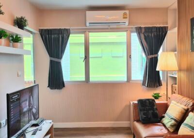 Cozy living room with a TV, couch, and window with curtains