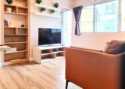 Modern living room with wooden flooring, open shelves, and a large window