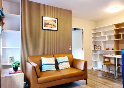 Modern living room with a brown leather sofa, wall art, and a study area