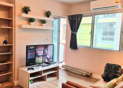 Modern living room with shelves, TV, air conditioning, and large window