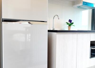 Modern kitchen area with a refrigerator, countertop, and sink