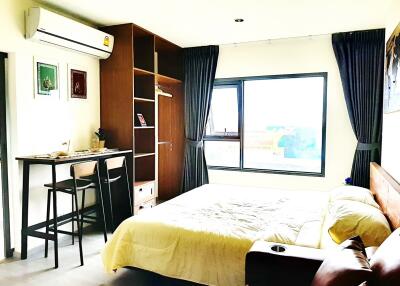 Modern bedroom with a large window, air conditioner, and wooden furniture.