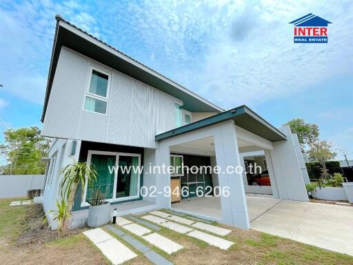 Two-story house exterior with driveway, windows, and small garden